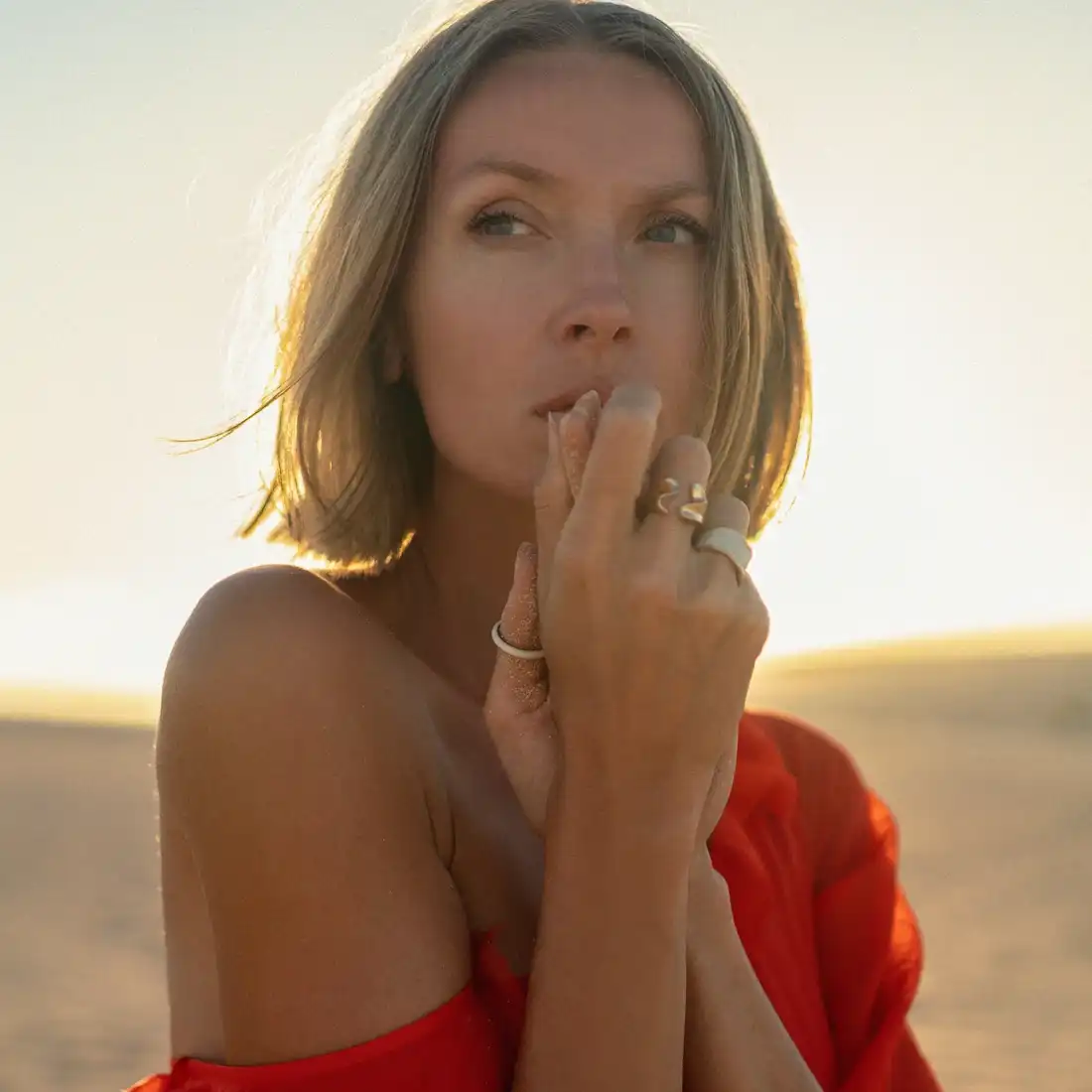 woman in red dress in desert with hand by her mouth looking to the side | BOTOX® in miami